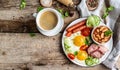 English breakfast. Fried eggs, sausages, bacon, beans, tomatoes and coffee cup on wooden table. Top view. copy space Royalty Free Stock Photo