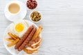 English breakfast with smoked sausages, scrambled eggs, bacon, mushrooms, toast and beans. Tea with milk. Breakfast on a white pla Royalty Free Stock Photo