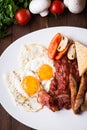 English breakfast (fried eggs, beans, roasted bacon, sausages and vegetables) on dark wood background Royalty Free Stock Photo