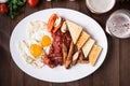 English breakfast (fried eggs, beans, roasted bacon, sausages and vegetables) on dark wood background Royalty Free Stock Photo