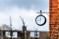 English brick house corner with dangling retro clock with Paddington Station London text on it