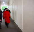 English figure with his back to the London royal family, wearing a long red coat