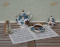 English teacup with saucer, teapot and sugar bowl and a metronome for music on a sheet of music