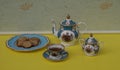 English teacup with saucer, teapot, sugar bowl and a cake plate with cookies, fine bone china porcelain