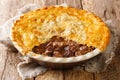 English homemade ale beef steak pie with crispy puff pastry close-up in a baking dish. horizontal