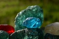 Stained glass from old glassworks smoothed and rounded in a mountain river collected by children beautifully stand out in the sun