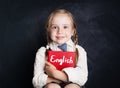 English language concept. Cute child pupil with book smiling