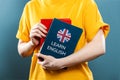 English Language Day. A woman holds English textbooks in her hands. Close-up of books. Blue background. The concept of learning Royalty Free Stock Photo