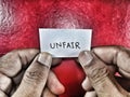 The english language word unfair written on the small paper