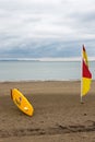 English lifeguard yellow board nd red and yellow flag on beach