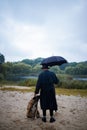 English man in stylish vintage coat and black hat walking in rainy forest with a dog. Royalty Free Stock Photo