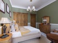 English-style bedroom with a large soft fabric bed. bedside tables with lamps. Large wardrobe and dresser with mirror