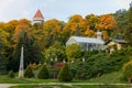 English-style park with glass greenhouse in autumn day, rose garden, statues near romantic medieval gothic and baroque castle