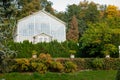 English-style park with glass greenhouse in autumn day, rose garden, statues near romantic medieval gothic and baroque castle