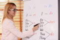 English teacher writing on whiteboard in class at lesson