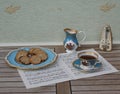 English teacup with saucer, cream jug and a cake plate with cookies and a metronome for music on a sheet of music