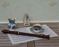 English teacup with saucer, cream jug, fine bone china porcelain, metronome for music and a block flute on a sheet of music