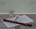 English teacup and saucer with floral decor and silver rim, metronome for music and a block flute on a sheet of music