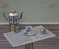 English teacup and saucer, silver-plated teapot on a silver stove and cream jug with floral decor on a sheet of music Royalty Free Stock Photo