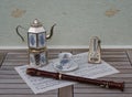 English teacup and saucer, silver-plated teapot on a silver stove, metronome for music and a block flute on a sheet of music