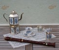 English teacup and saucer, silver-plated teapot, spoon vase, teaspoon and cream jug and a block flute on a sheet of music