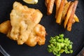 English Traditional Fish and chips with mashed minty peas, tartar sauce vertical side view on black plate close up details side Royalty Free Stock Photo