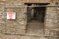 English Warning sign Danger Keep Out. Fence barrier in front of a stone entry . Keep your distance funny sign Royalty Free Stock Photo