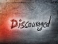 the English word discouraged written by pencil on the grey and orange wall background texture Royalty Free Stock Photo