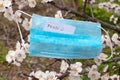 The English word pause on a sheet lies on a medical mask that hangs on apricot branches in the spring during the quarantine period