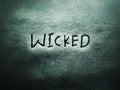 the english word wicked on the grunge rough grain wall texture background Royalty Free Stock Photo