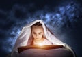 Engrossed little girl reading book in bed Royalty Free Stock Photo