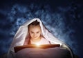 Engrossed little girl reading book in bed Royalty Free Stock Photo