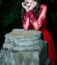 Enigmatic Gothic Beauty - Slender Woman Pondering in Crimson Red Elegance Royalty Free Stock Photo