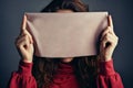 Enigmatic image Woman hiding face behind a sheet of paper