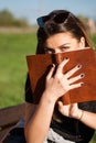 Enigmatic Reader: Young Woman Immersed in a Retro Book at the Park