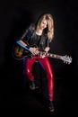 Enigmatic, stylish blonde girl guitarist plays by electric guitar in leather jacket. Woman teacher shows how to play Royalty Free Stock Photo