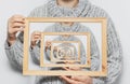 Enigmatic surrealistic optical illusion, young man holding frame on white background. Royalty Free Stock Photo