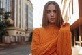 Enigmatic young woman in orange braided sweater with long sleeves