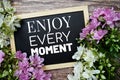 Enjoy Every Moment typography text written on wooden blackboard with flower bouquet decorate on wooden background Royalty Free Stock Photo