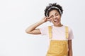 Enjoy life and chill. portrait of joyful carefree beautiful African American in yellow overalls and headband, tilting