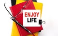 ENJOY LIFE text written on a sticky on colorful notebooks