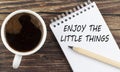 ENJOY THE LITTLE THINGS text on notebook with coffee on the wooden background Royalty Free Stock Photo