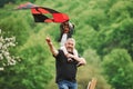 Enjoy the moment. Running with red kite. Child sitting on the man`s shoulders. Having fun