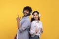 Enjoy music together. Happy young indian couple in wireless headphones listening songs and dancing, yellow background Royalty Free Stock Photo