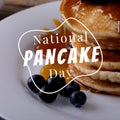 Enjoy national pancake day text in white over pancake stack on plate with blueberries and syrup