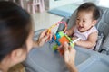 Asian mother playing toy with her baby sitting on the dinning chair. Royalty Free Stock Photo