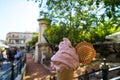 Enjoy sparkled melting pink strawberry ice cream soft serve cone and crispy waffle along sidewalk with blurred people background