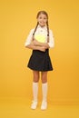 Enjoy studying. Exciting literature. Girl child hold book stand yellow background. Schoolgirl studying textbook. Kid