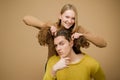 Enjoy twogether. A blonde girlfriend making funny hairstyle to her boyfriend with curly hair. Young couple doing a joke Royalty Free Stock Photo