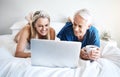 We enjoy watching tons of shows together. a mature couple using a laptop while relaxing on their bed at home. Royalty Free Stock Photo